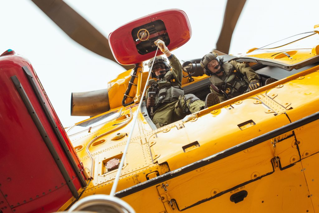 A yellow helicopter with two people rescuing someone