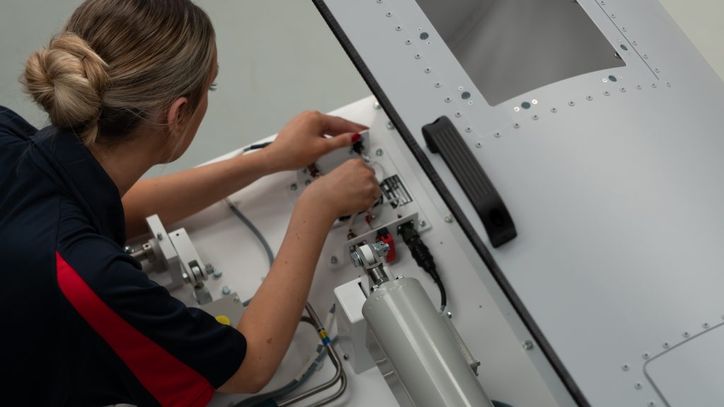 A person fixing wiring and cabling on a hardware training device