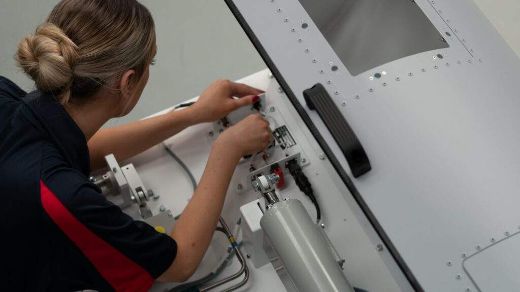 A person fixing wiring and cabling on a hardware training device