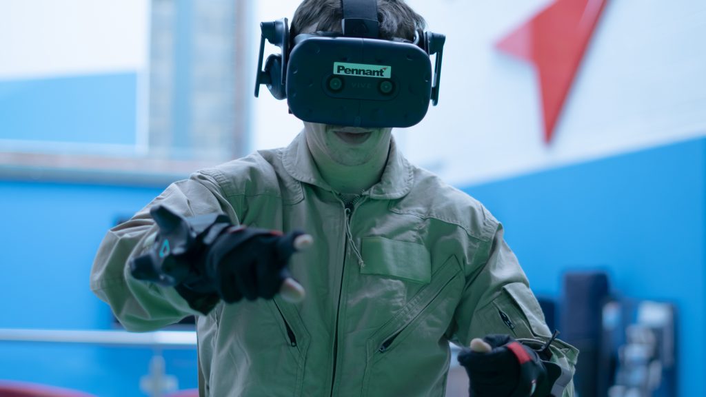 A person in a VR headset. The headset is branded with the words "pennant"