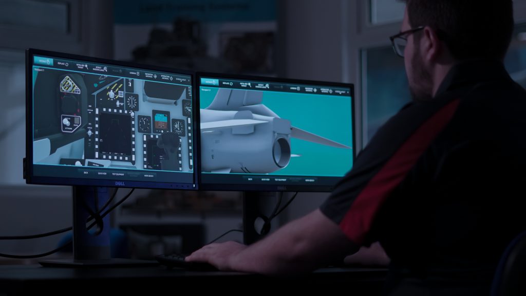 Two desktop screens with an emulation on the screen of an aircraft. There is a person sat at the desktop using the computer.