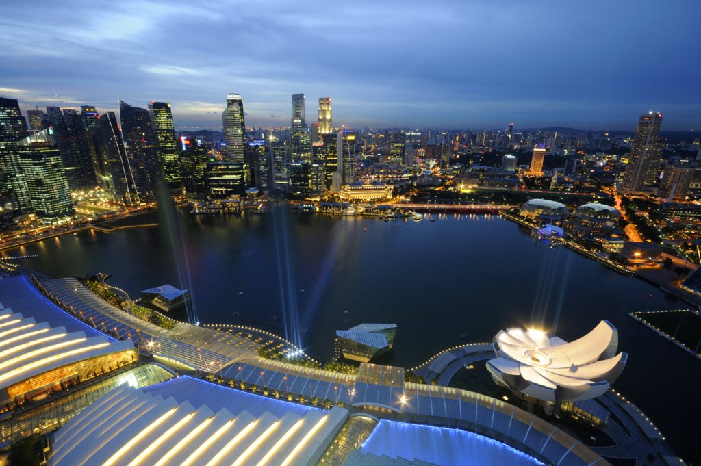 Pennant win Order for Training in Singapore from Kawasaki Heavy Industries 20 Overlooking the Marina Bay in Singapore. There is a river in the middle of the image and lots of buildings with lights.