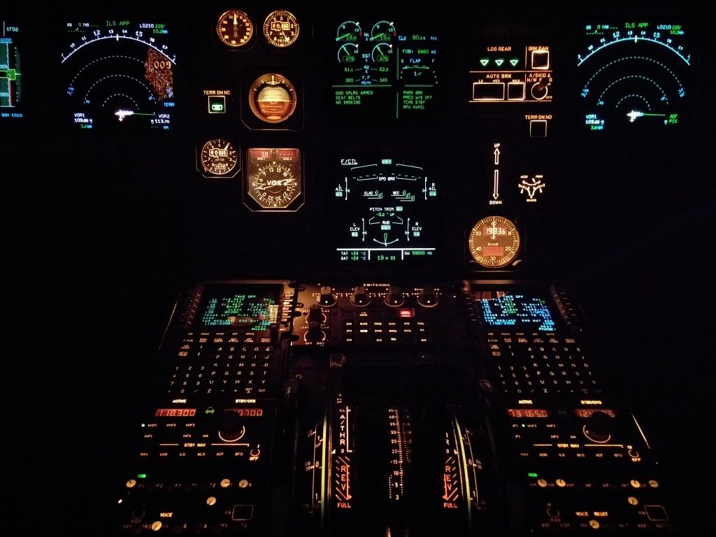 Cockpit view at night with illuminated flight instruments and controls
