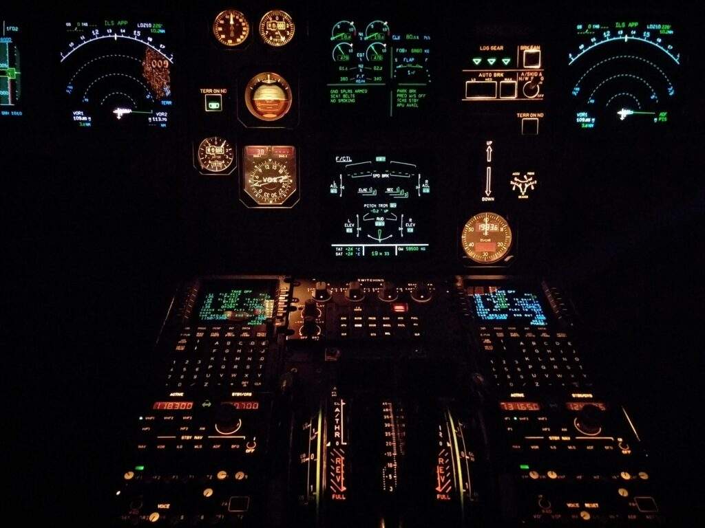 Cockpit view at night with illuminated flight instruments and controls