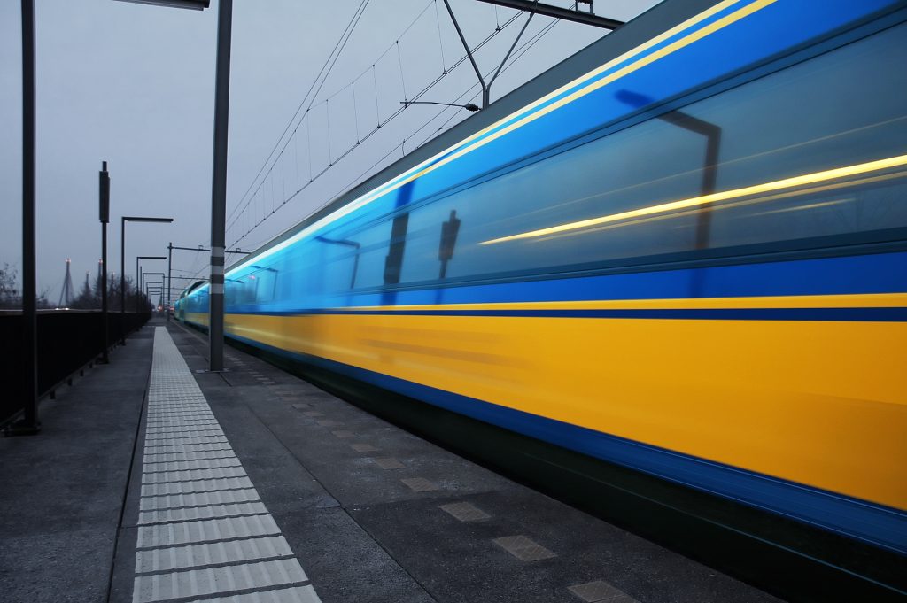 A blue and yellow train speeding down a platform at a train station