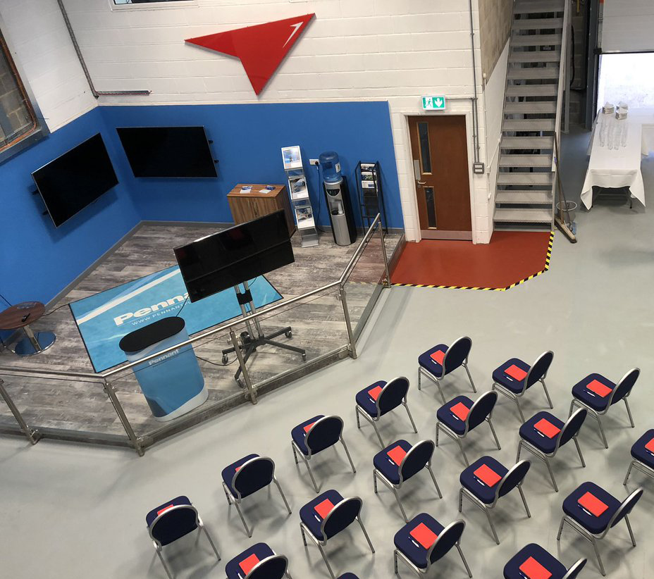 A photo looking down on a room. There is a number of chairs and screens set-up in a room ready for a presentation