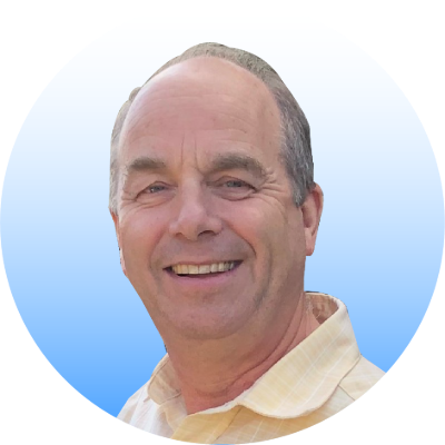 Photo of a man, Graham Brum, wearing a yellow shirt, smiling at the camera. 
