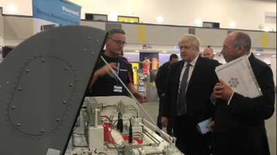 A number of people stood around a hardware training equipment. One of the people is Boris Johnstone the Prime Minister.