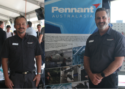 Two people standing in front of a sign that says "Pennant Australasia"