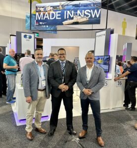 A collage of images from a trade show featuring people with faces blurred standing near various exhibits including ‘MADE IN NSW’, and military equipment displays by EOS and RADIO MARINE